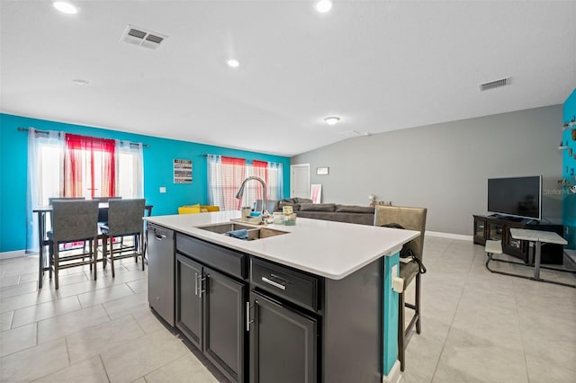 kitchen featuring a kitchen island with sink, a breakfast bar, sink, light tile floors, and dishwasher