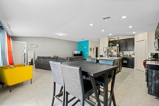 tiled dining space featuring sink and vaulted ceiling