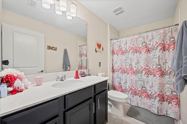 bathroom with toilet, large vanity, and tile flooring