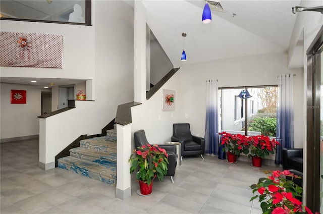 staircase with high vaulted ceiling and light tile floors