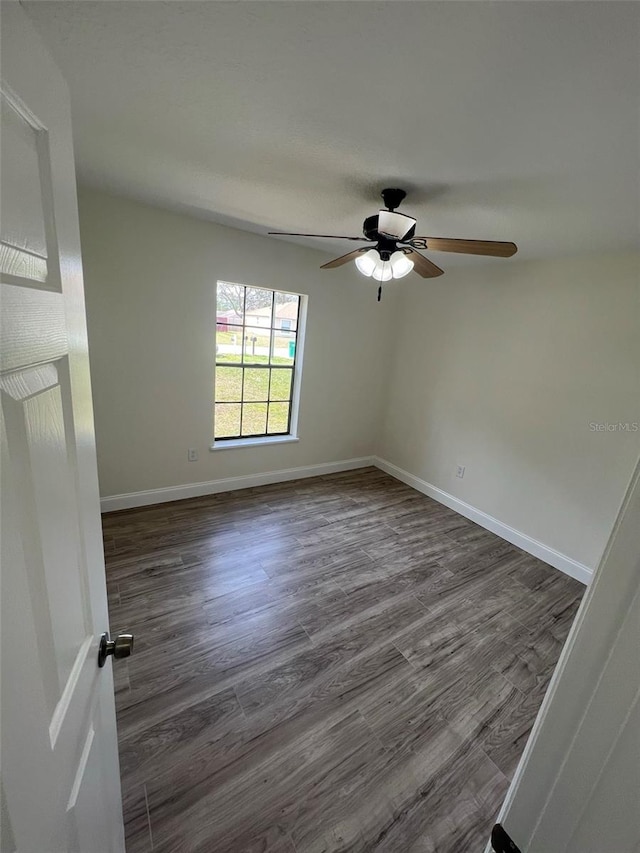 empty room with ceiling fan and dark hardwood / wood-style flooring