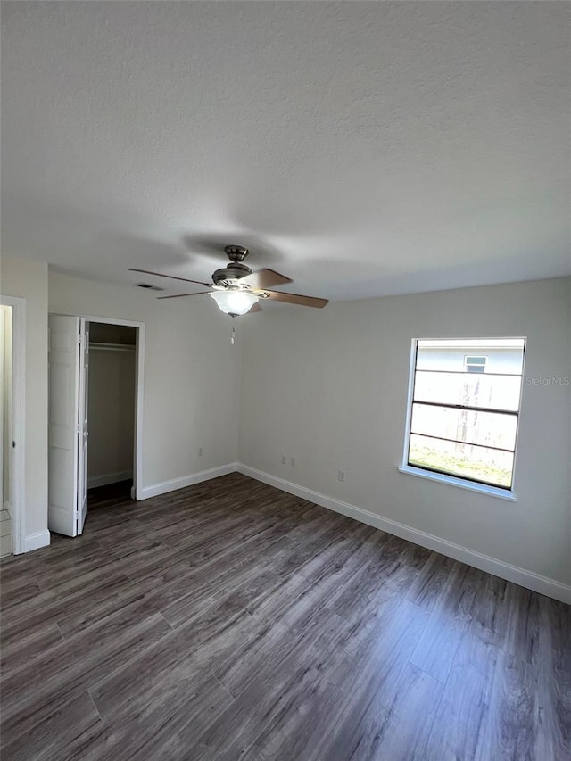 unfurnished bedroom with a textured ceiling, ceiling fan, dark hardwood / wood-style floors, and a closet