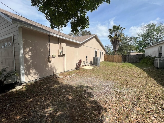 view of yard with central AC and a garage