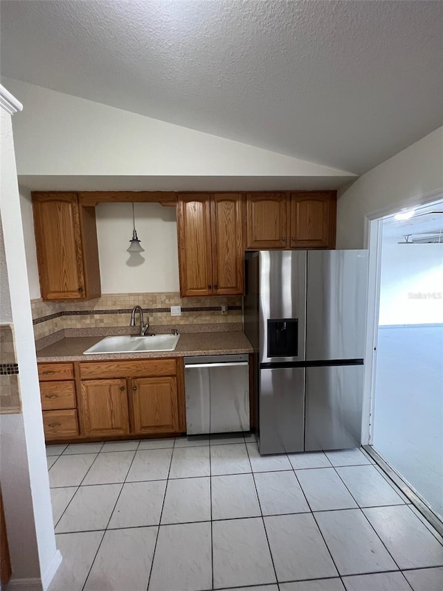 kitchen with light tile patterned floors, appliances with stainless steel finishes, sink, lofted ceiling, and decorative backsplash