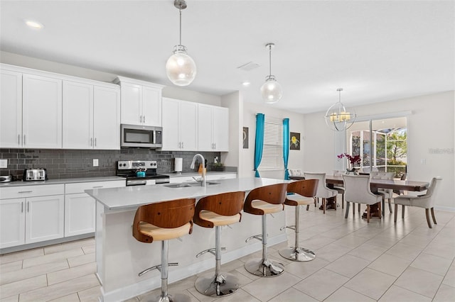 kitchen with hanging light fixtures, stainless steel appliances, and white cabinetry