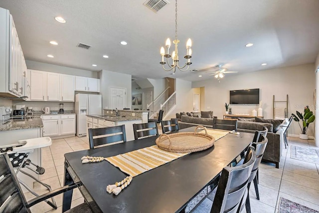 tiled dining space with ceiling fan with notable chandelier and sink