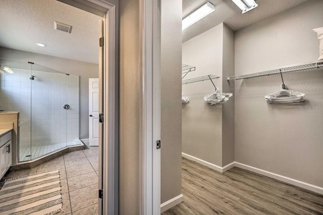 bathroom featuring vanity, a textured ceiling, hardwood / wood-style flooring, and walk in shower