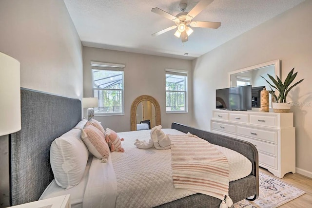 bedroom with a textured ceiling, light hardwood / wood-style floors, and ceiling fan