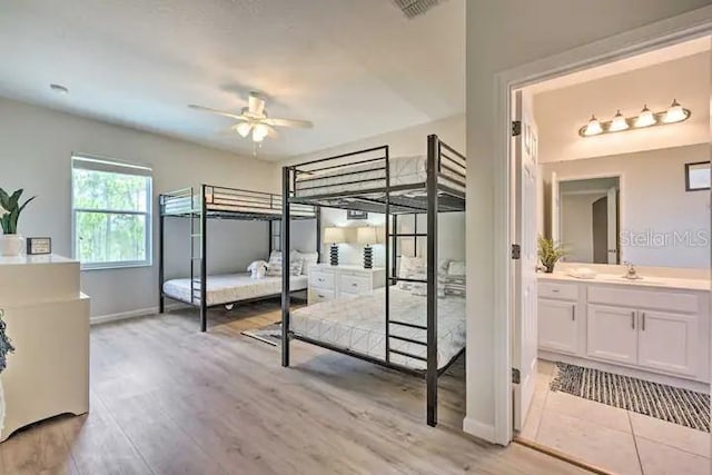 bedroom with ceiling fan, light hardwood / wood-style flooring, sink, and connected bathroom