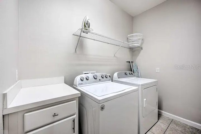 laundry room featuring cabinets, light tile flooring, and washing machine and dryer