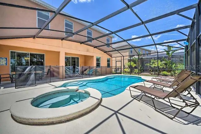 view of pool with an in ground hot tub, glass enclosure, and a patio