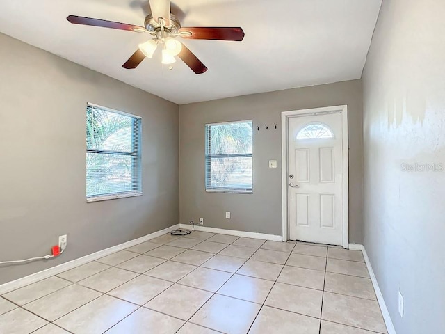 foyer featuring ceiling fan, light tile floors, and a wealth of natural light