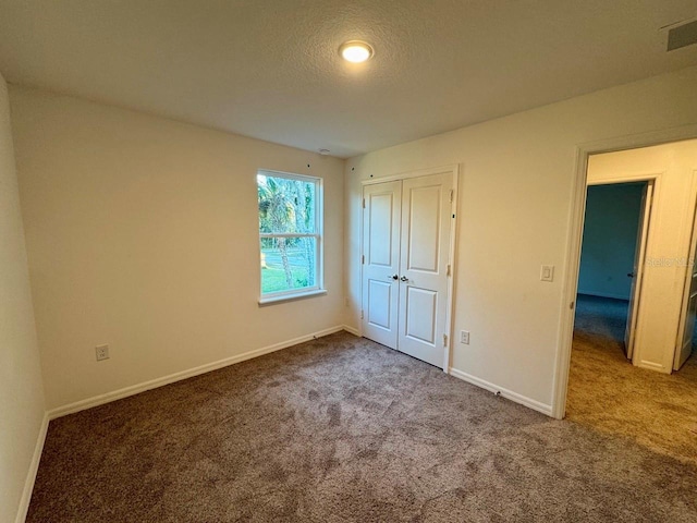 unfurnished bedroom featuring carpet flooring, a textured ceiling, and a closet