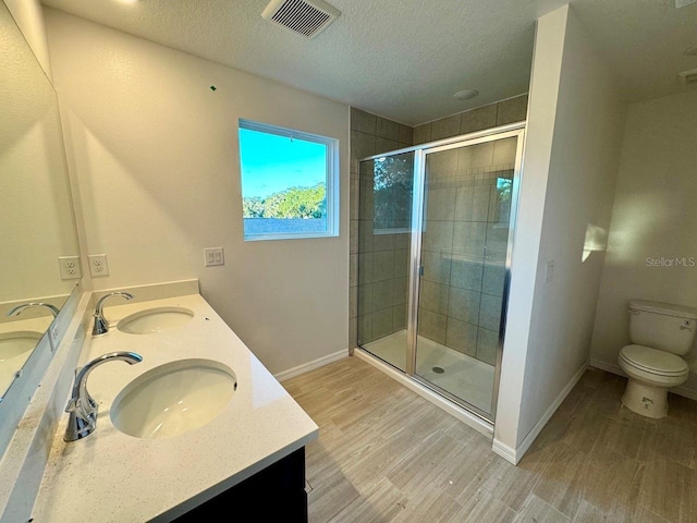 bathroom with vanity, a textured ceiling, a shower with shower door, and toilet