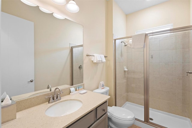 bathroom featuring an enclosed shower, toilet, and vanity