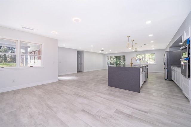 kitchen featuring a notable chandelier, decorative light fixtures, a center island with sink, light hardwood / wood-style flooring, and sink