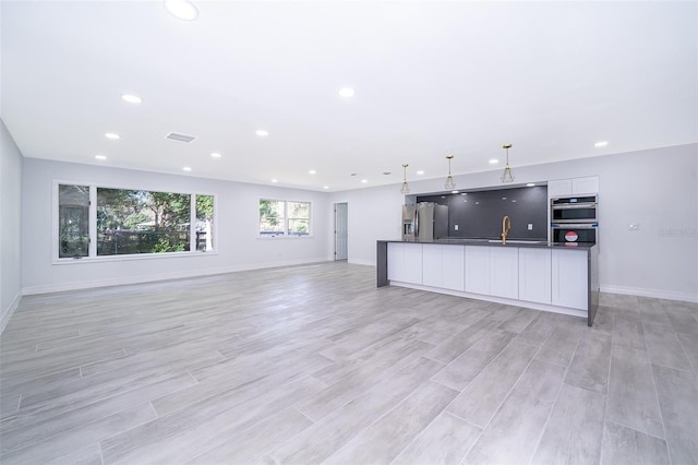 unfurnished living room with sink and light wood-type flooring