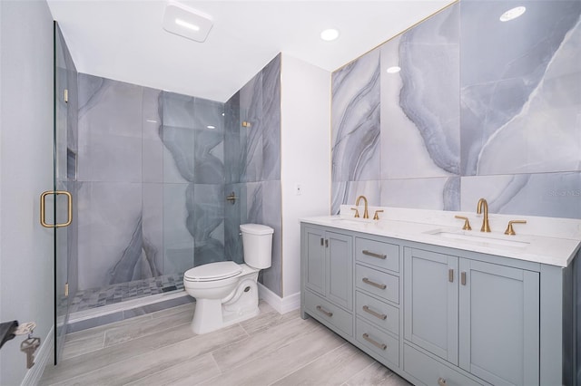 bathroom with dual vanity, a shower with shower door, toilet, and tile walls