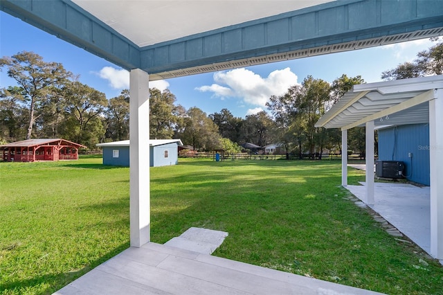 view of yard featuring an outdoor structure, central AC unit, and a pergola