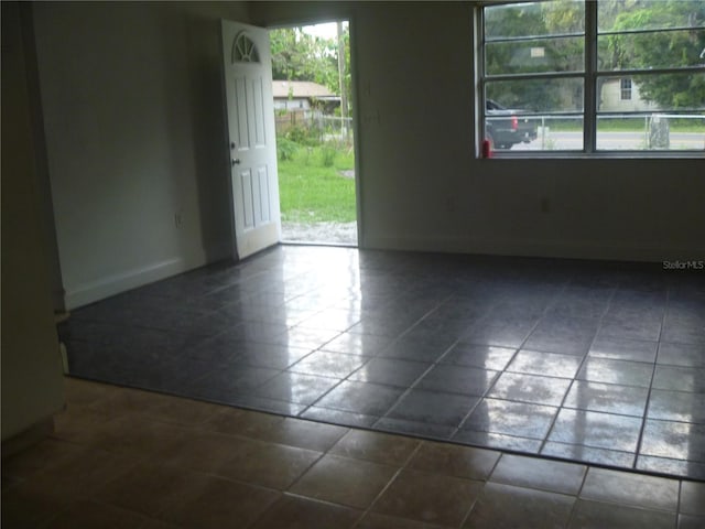 spare room featuring a wealth of natural light and dark tile floors