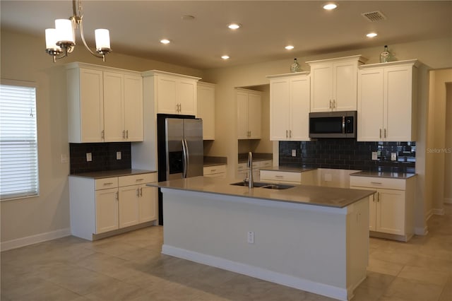 kitchen featuring an inviting chandelier, appliances with stainless steel finishes, sink, a center island with sink, and tasteful backsplash