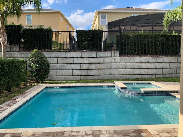 view of swimming pool with glass enclosure and an in ground hot tub