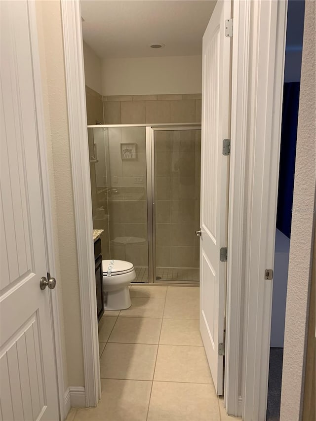 bathroom with vanity, toilet, tile patterned floors, and a shower with shower door