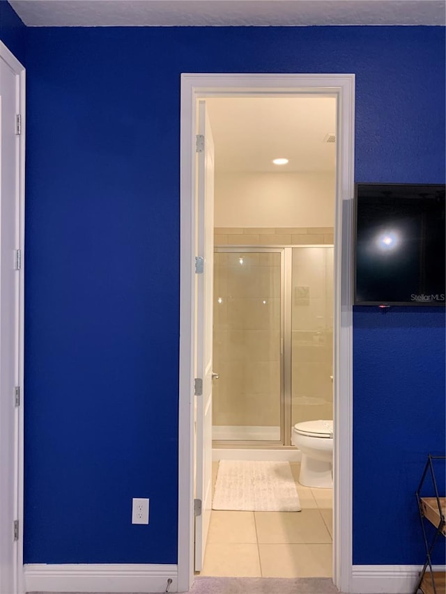 bathroom with toilet, an enclosed shower, and tile patterned flooring