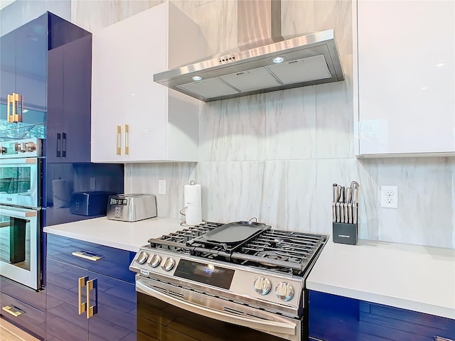 kitchen with wall chimney range hood, white cabinets, backsplash, and appliances with stainless steel finishes