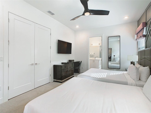 bedroom with light carpet, ensuite bath, a closet, and ceiling fan