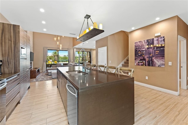 kitchen with a notable chandelier, a center island with sink, hanging light fixtures, dishwasher, and sink