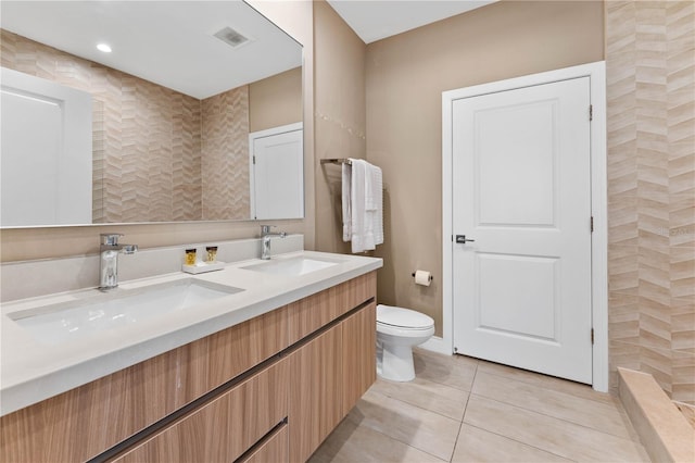 bathroom featuring tile floors, toilet, large vanity, and dual sinks