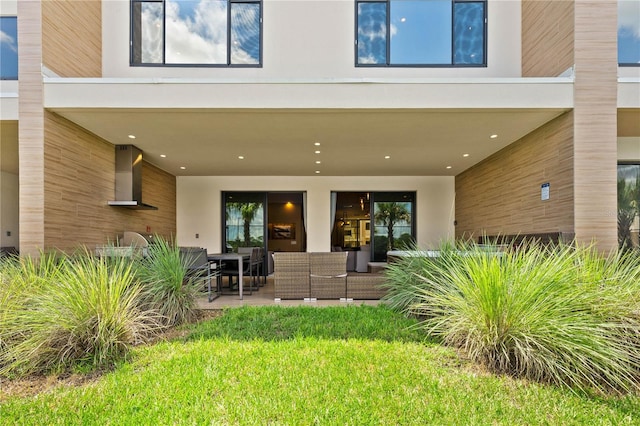 back of property with a lawn and a patio