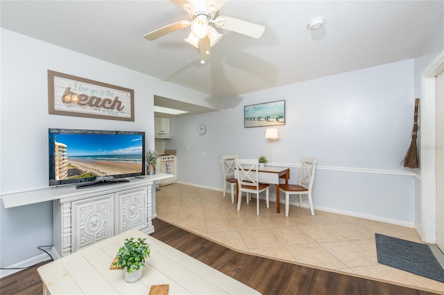 living room with light hardwood / wood-style floors, a textured ceiling, and ceiling fan