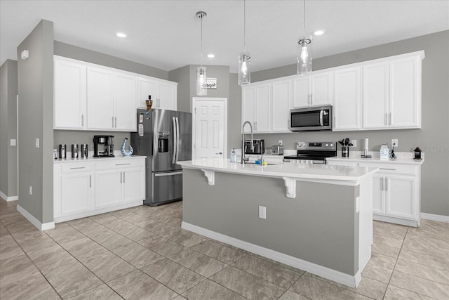 kitchen featuring a kitchen island with sink, light tile floors, appliances with stainless steel finishes, a breakfast bar area, and white cabinetry