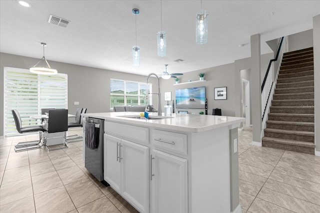 kitchen with hanging light fixtures, white cabinetry, a kitchen island with sink, light tile floors, and dishwasher