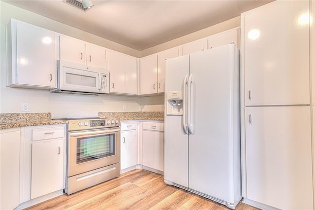 kitchen with light stone counters, white cabinets, white appliances, and light hardwood / wood-style floors