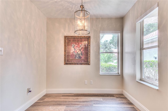 unfurnished room with hardwood / wood-style flooring and a chandelier