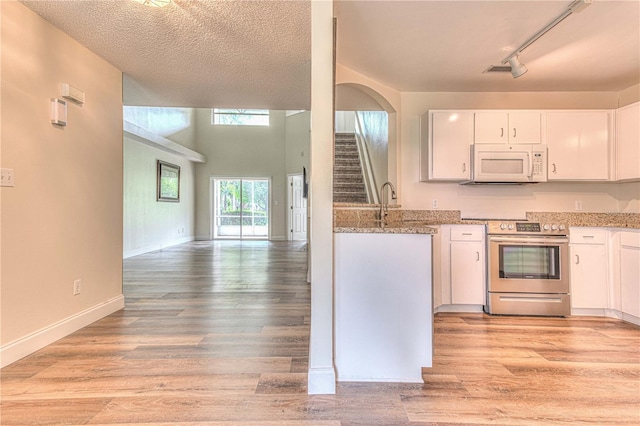 kitchen with white cabinets, stainless steel range with electric cooktop, light stone counters, a textured ceiling, and light hardwood / wood-style flooring