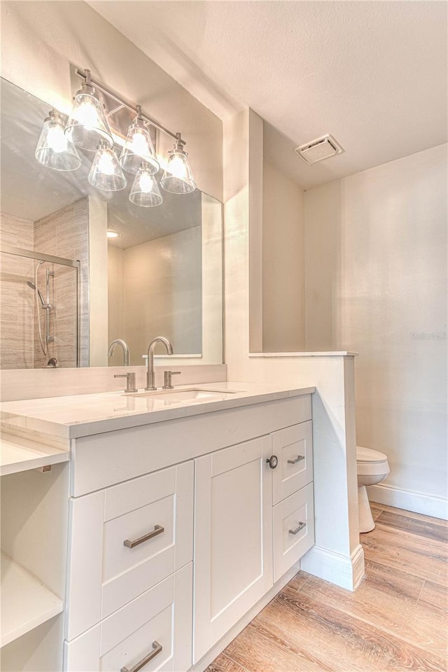 bathroom featuring toilet, an enclosed shower, wood-type flooring, a textured ceiling, and vanity