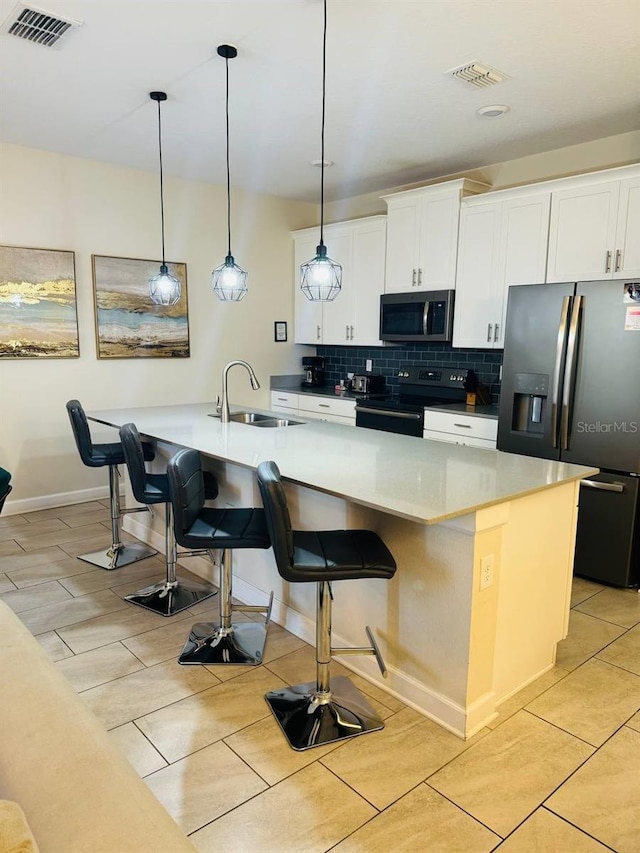 kitchen with hanging light fixtures, backsplash, appliances with stainless steel finishes, a kitchen bar, and sink