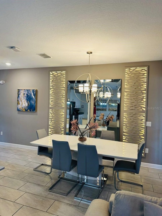 dining space featuring a textured ceiling, a notable chandelier, and light tile floors