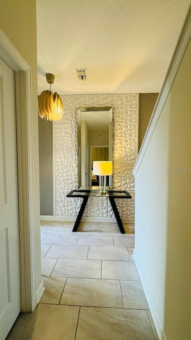 corridor featuring light tile floors and a textured ceiling