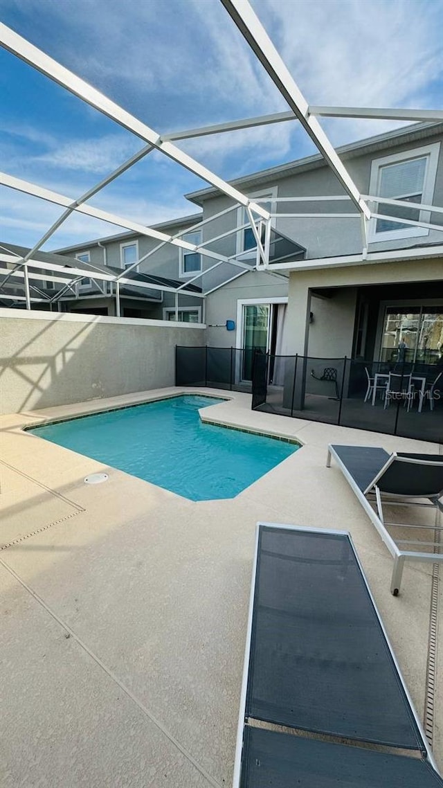 view of swimming pool featuring a patio area and glass enclosure