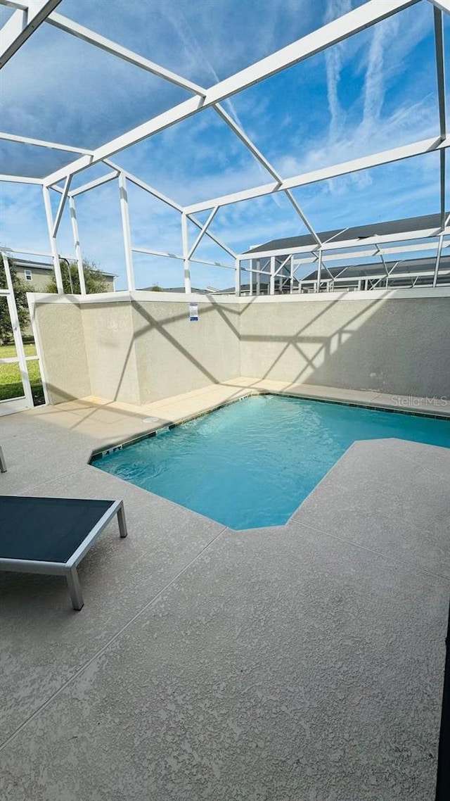 view of swimming pool with a patio area and a lanai