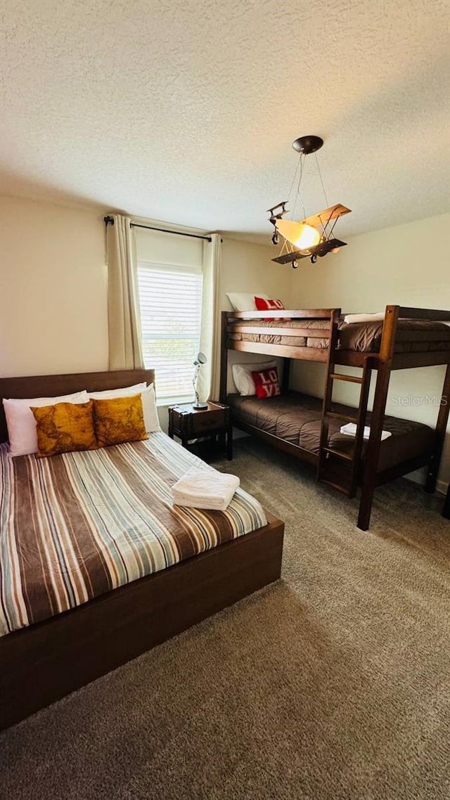 bedroom featuring a textured ceiling and dark colored carpet