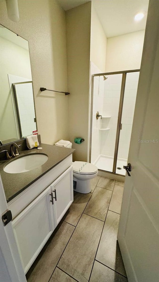 bathroom featuring walk in shower, toilet, tile floors, and oversized vanity