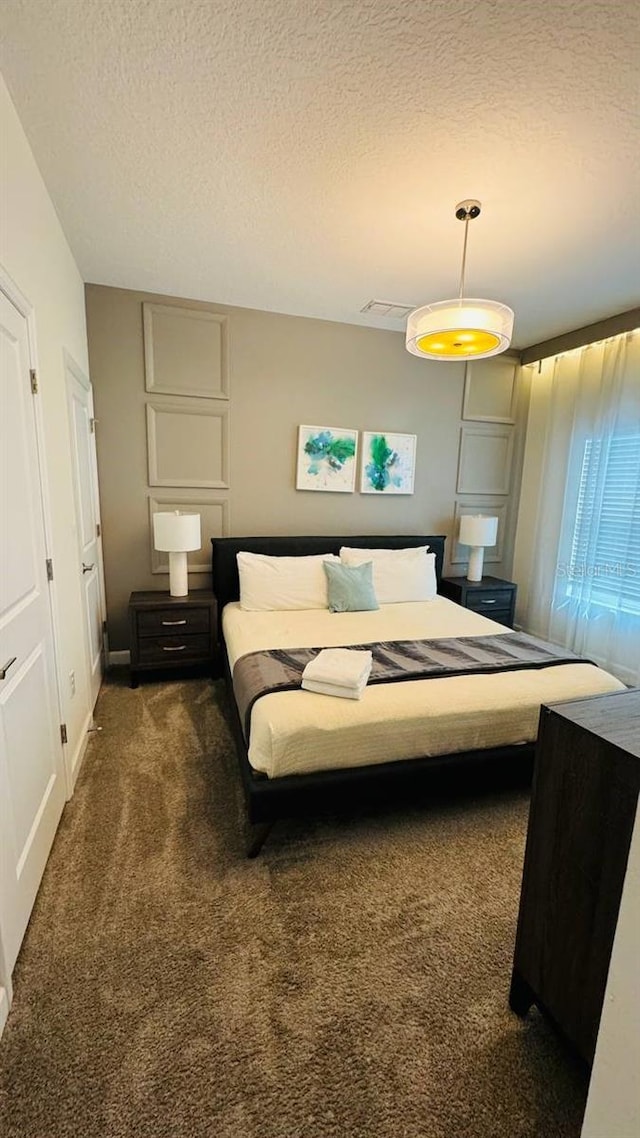 bedroom featuring a textured ceiling and dark colored carpet