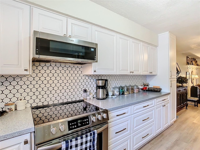 kitchen with backsplash, stainless steel appliances, and white cabinets