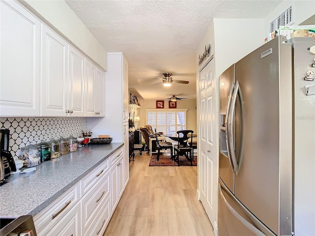 kitchen with light hardwood / wood-style flooring, white cabinetry, stainless steel refrigerator with ice dispenser, tasteful backsplash, and a textured ceiling